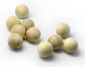 May include: A collection of eleven unfinished wooden spheres, each approximately 1 inch in diameter, scattered on a white surface. The spheres have a natural wood grain and a light tan color, suitable for crafts and DIY projects.