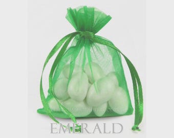 May include: A sheer emerald green organza drawstring pouch filled with several smooth white oval-shaped candies. The bag features a matching green ribbon tie at the top and the text EMERALD is printed in a dark font at the bottom of the image.