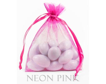 May include: A neon pink sheer organza drawstring pouch filled with several smooth, light lavender oval-shaped candies. The bag features a translucent fabric texture and matching pink ribbon ties at the top. The text "etsy.com/shop/sheercolors" and "NEON PINK" are visible.