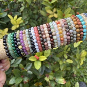 May include: A white ceramic mug with a black handle and the text "But First, Coffee" in a black, bold font. The mug is sitting on a white surface. The mug is approximately 4 inches tall.