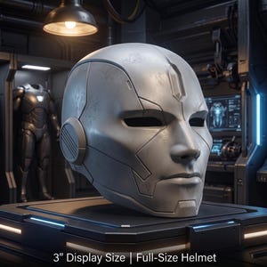 May include: A matte grey, full-size helmet featuring a smooth, contoured faceplate with integrated eye slits and a central forehead detail. The helmet includes circular side ear pieces and displays the text 3" Display Size | Full-Size Helmet.