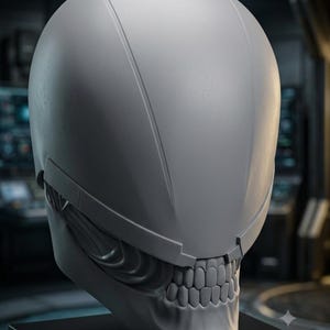 May include: A matte gray helmet featuring a smooth, rounded upper dome and a lower section sculpted with visible human-like teeth and jaw structure. The design includes a horizontal band separating the dome from the lower facial features.