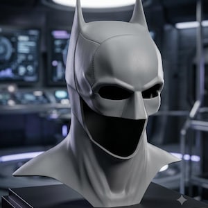 May include: A gray, full-head cowl mask featuring pointed bat-like ears, a structured forehead, and a wide opening for the eyes and mouth. The mask displays visible seam lines along the sides and top, with a smooth, matte finish throughout.