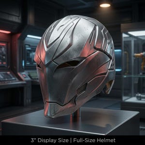 May include: A metallic silver helmet with a sleek, angular design and weathered texture. The helmet features narrow eye slits and complex paneling. Text at the bottom reads: 3" Display Size | Full-Size Helmet. The object is mounted on a stand.