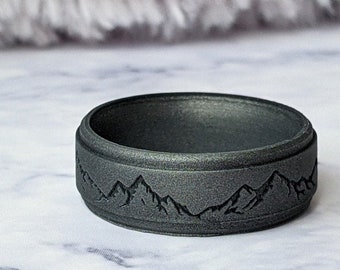 May include: A dark gray silicone ring with a mountain range design engraved on the band.