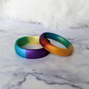 Puede incluir: Dos anillos de silicona con un dise&ntilde;o degradado arco&iacute;ris. El anillo de arriba es un degradado de amarillo a naranja, y el anillo de abajo es un degradado de verde a morado.