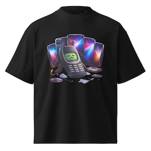 May include: Black t-shirt featuring a graphic of a vintage cell phone with a sad face, surrounded by modern smartphones. The design includes a lit fuse and scattered debris, creating a commentary on technology.