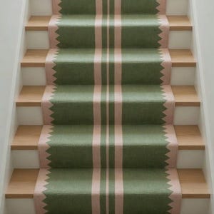 May include: A stair runner featuring a repeating pattern of sage green and soft pink. The design includes a central vertical stripe flanked by two thinner lines, with jagged, sawtooth-style edges along both sides of the runner.
