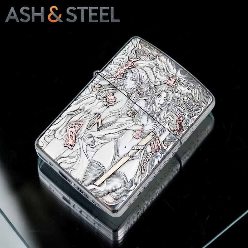 May include: A silver lighter with an engraved design featuring two female figures with long hair and a sword. The lighter has the text "ASH & STEEL" at the top. The design is detailed with pink and gold accents.