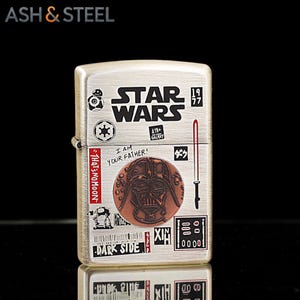K&ouml;nnte beinhalten: Ein silberfarbenes Metallfeuerzeug mit Star Wars-Grafiken. Das Design umfasst das Star Wars-Logo, das Bild von Darth Vader und den Text "I AM YOUR FATHER!" und "DARK SIDE". Das Feuerzeug hat eine rechteckige Form und einen Klappdeckel.