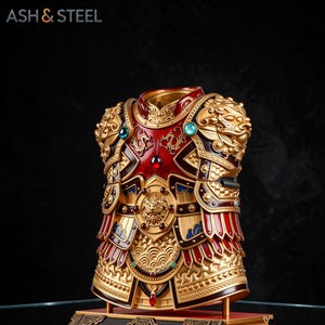 May include: Ornate, gold-colored decorative armor with red and black accents. The armor features intricate detailing, including dragon motifs and jewel-toned embellishments. The text "ASH & STEEL" is visible at the top.