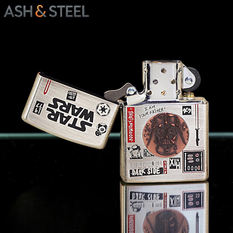 K&ouml;nnte beinhalten: Ein silberfarbenes Metallfeuerzeug mit Klappdeckel, verziert mit Star Wars-Grafiken und dem Text "I AM YOUR FATHER!". Das Design beinhaltet Bilder von Darth Vader und anderen ikonischen Elementen der Filmreihe.