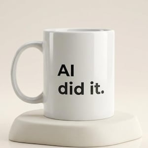 May include: White ceramic mug with the text "AI did it" in black, displayed on a white, rounded square coaster. The mug has a curved handle and is set against a neutral background.