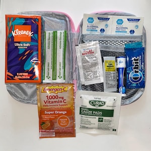 Può includere: Una custodia con cerniera contenente vari articoli per la cura personale e il primo soccorso, tra cui un pacchetto di fazzoletti Kleenex, cerotti, salviette imbevute di alcol, crema per ustioni, pomata antibiotica, balsamo labbra, gomma Orbit, Emergen-C e garze.