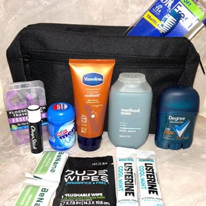 May include: A black travel bag containing toiletries. Contents include a toothbrush, toothpaste, lip balm, deodorant, body wash, lotion, mouthwash, floss, and wipes. The bag has a zip and a handle.