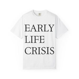 May include: White t-shirt with the words "EARLY LIFE CRISIS" printed in black, centered on the front. The shirt has a crew neck and short sleeves. The text is in a bold, sans-serif font.