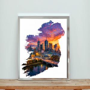May include: Framed print depicting a cityscape within the shape of Ireland. The artwork displays a vivid sunset with hues of orange, purple, and blue. The city skyline includes tall buildings, a bridge, and a river.