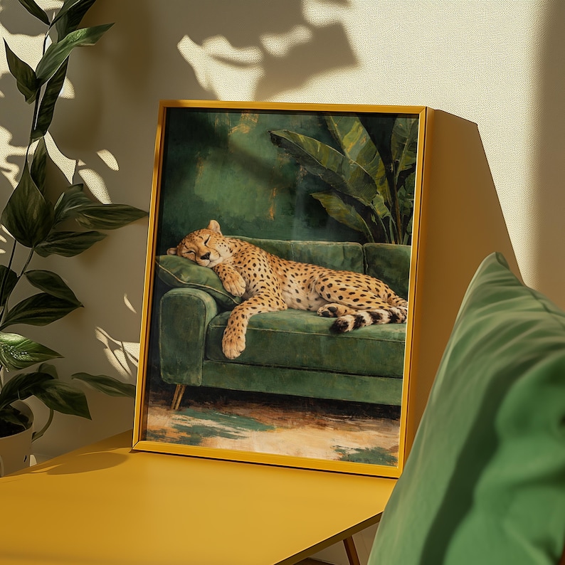 May include: A framed art print featuring a sleeping cheetah on a green velvet sofa. The artwork has a gold frame and depicts a lush green background with tropical plants. The cheetah has a tan coat with black spots.