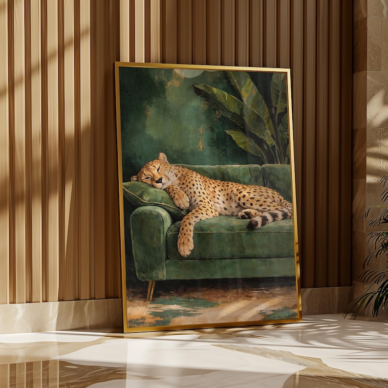 May include: A framed art print featuring a sleeping cheetah on a green velvet sofa. The artwork has a gold frame and is set against a backdrop of lush green foliage and a dark green background. The cheetah's fur is spotted with black markings.