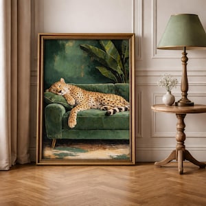 May include: A framed artwork depicts a cheetah resting on a green velvet sofa. The cheetah's spotted coat contrasts with the sofa's color. The background features a green wall and large tropical leaves. The artwork is in a gold frame.