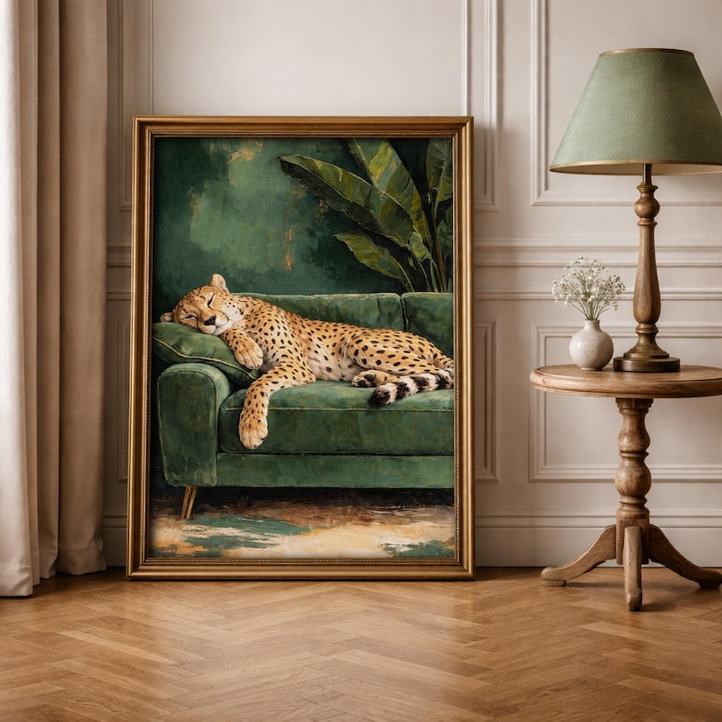 May include: A framed artwork depicts a cheetah resting on a green velvet sofa. The cheetah's spotted coat contrasts with the sofa's color. The background features a green wall and large tropical leaves. The artwork is in a gold frame.