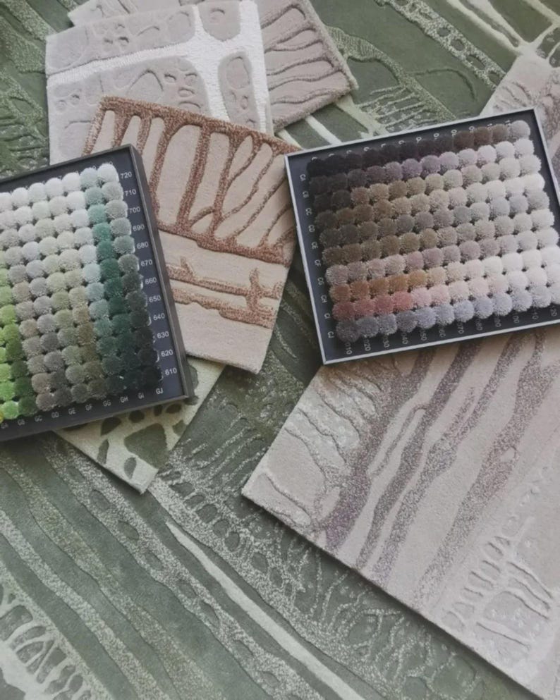 May include: A collection of carpet samples and color swatches. The samples feature various textures and patterns in neutral tones, including beige, brown, and green. Color swatches display a range of shades for design selection. The image showcases options for flooring and interior design.