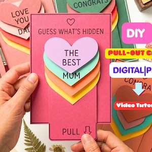 Könnte beinhalten: Eine rosafarbene, rechteckige Ausziehkarte mit dem Text GUESS WHAT'S HIDDEN und PULL mit einem Pfeil. Die Karte zeigt einen Stapel geschichteter Papierherzen in Lavendel, Türkis, Orange und Gelb, bedruckt mit dem Text THE BEST MOM.