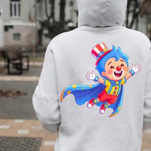 Puede incluir: Sudadera con capucha blanca con un colorido dibujo de un payaso de dibujos animados en la espalda. El payaso lleva un sombrero rojo, blanco y azul, una capa azul con estrellas y un atuendo amarillo y rojo. El payaso sonr&iacute;e y tiene los brazos extendidos.