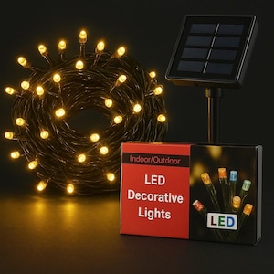 May include: A coil of warm white LED decorative lights with a solar panel and a red box. The box reads "Indoor/Outdoor LED Decorative Lights". The lights are on a dark wire and are lit up. The solar panel is black.