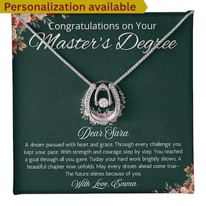 May include: A silver horseshoe pendant necklace with a central clear stone, presented on a dark green card with floral accents. The card reads "Congratulations on Your Master's Degree" and includes a personalized message.