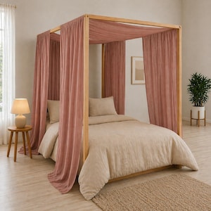 Könnte beinhalten: Ein Himmelbett mit hellem Holzrahmen und altrosa Vorhängen. Das Bett ist mit beiger Bettwäsche und Kissen ausgestattet. Links ein kleiner Beistelltisch mit Lampe, rechts eine Topfpflanze.