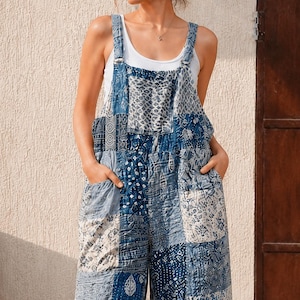 Könnte beinhalten: Eine blau-weiße Latzhose im Patchwork-Stil mit einer Vielzahl komplizierter Muster, darunter florale, geometrische und abstrakte Designs. Das Kleidungsstück hat weite Beine, zwei Vordertaschen und verstellbare Schulterträger über einem weißen Tanktop.