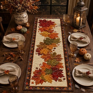 May include: A rectangular table runner featuring a cream-colored center with a central pattern of embroidered autumn leaves in shades of red, orange, yellow, and green, bordered by a dark brown frame with a small leaf print and stitched details.