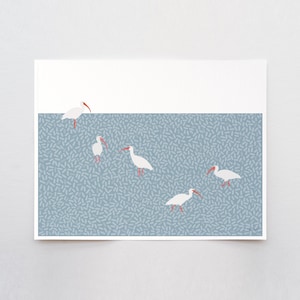 Peut inclure: Une impression représentant cinq ibis blancs avec des becs et des pattes rouges, sur un fond bleu avec un motif de petites formes bleu clair. La partie supérieure est blanche.