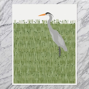 May include: A grey heron with an orange beak stands in a field of green grass.