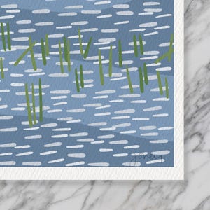 May include: A square art print featuring a stylized blue water surface with horizontal white dashes representing ripples and vertical green blades of grass emerging from the water. The artist's signature is visible in the bottom right corner.