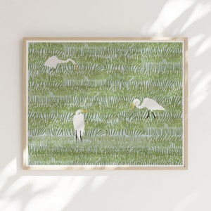 May include: A framed print of three white egrets standing in a field of green grass. The egrets are depicted in a stylized, graphic style.