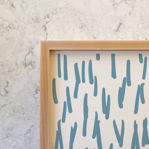 May include: A framed print with a white background and a repeating pattern of blue abstract shapes. The shapes resemble lines and squiggles.