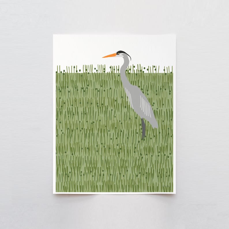 May include: A grey heron with an orange beak stands in a field of green grass.