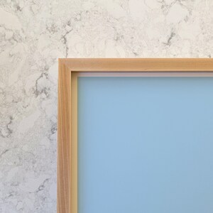 May include: A light blue picture frame with a natural wood finish. The frame is made of wood and has a simple, modern design.