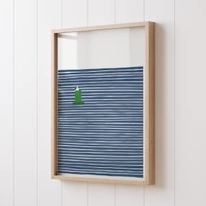 May include: A framed print of a green lighthouse on a blue and white striped background. The lighthouse is in the center of the image and is surrounded by the stripes.