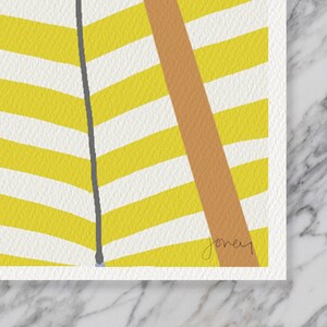 May include: Abstract art print with a yellow and white chevron design, a diagonal tan stripe, and a grey vertical line. The artist's signature, "joney", is in the bottom right corner. The artwork is on textured paper.