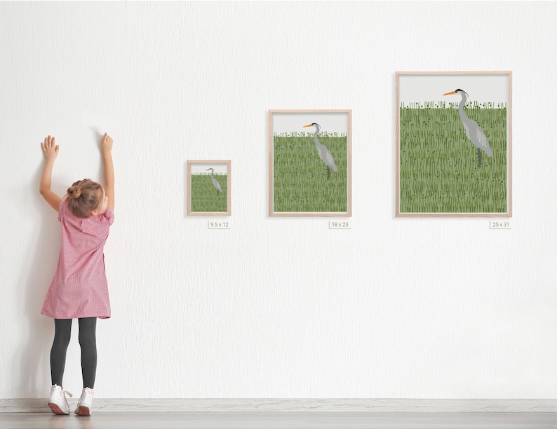 May include: A framed print of a grey heron standing in a field of green grass. The print is available in three sizes: 8x12 inches, 18x23 inches, and 25x31 inches.