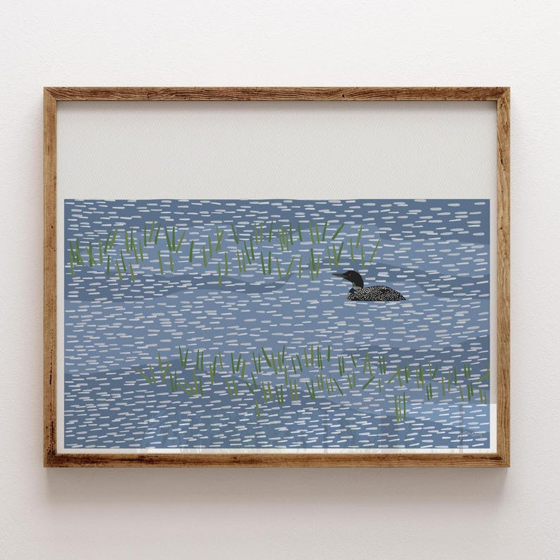 May include: A framed art print featuring a stylized illustration of a black and white loon swimming in blue water with small white dashes representing ripples and green vertical lines depicting aquatic plants in the foreground.