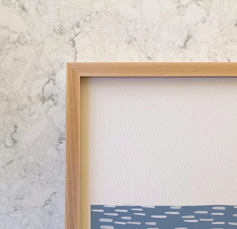 May include: A rectangular wall art piece featuring a light wood frame surrounding a textured off-white paper background. The lower portion of the artwork displays a horizontal band of blue with a repeating pattern of small white dashes.