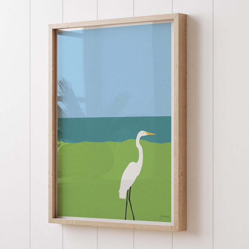 May include: A framed illustration of a white egret standing on a green grassy area with a blue ocean in the background.