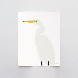 May include: A minimalist art print featuring a white egret bird with a yellow beak and eye details. The bird is depicted in a simple, graphic style against a white background. The artwork has a modern, clean aesthetic.