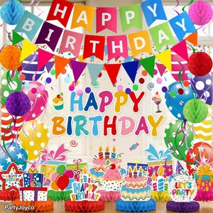 May include: A colorful birthday party decoration set featuring a "HAPPY BIRTHDAY" banner with pennants, honeycomb paper balls in various colors, and table centerpieces shaped like cakes and gift boxes with "HAPPY BIRTHDAY" and "LET'S PARTY" text.