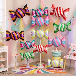 May include: A collection of candy-shaped foil balloons in various colors and patterns, including striped designs in orange and black, red and white, green and white, and pastel multi-colored combinations, displayed on stands and as wall decor.