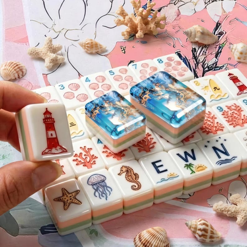 May include: A set of rectangular mahjong tiles featuring nautical and ocean-themed illustrations including a red and white lighthouse, a starfish, a jellyfish, a seahorse, and the letters E, W, and N. Two tiles display a blue resin ocean scene.